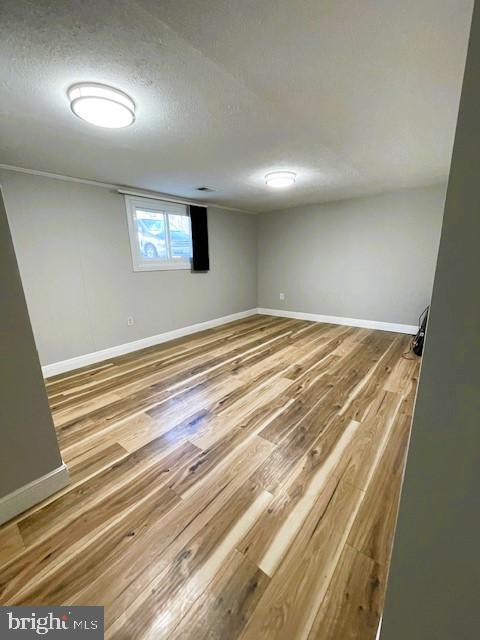 basement with wood-type flooring and a textured ceiling