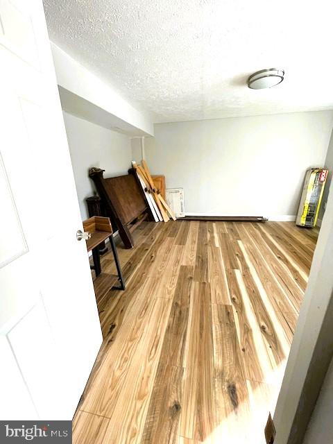 additional living space with a textured ceiling and light hardwood / wood-style floors