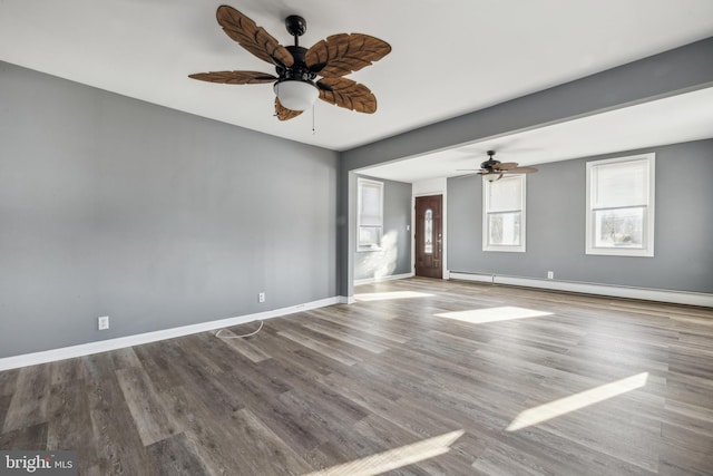 empty room featuring a baseboard heating unit, ceiling fan, and wood-type flooring