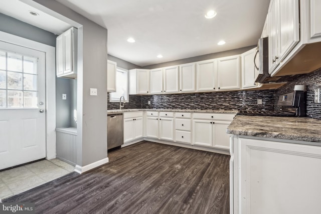 kitchen featuring white cabinetry, appliances with stainless steel finishes, dark wood-type flooring, dark stone counters, and sink