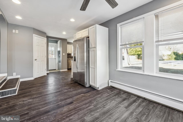 interior space featuring white cabinetry, stainless steel refrigerator with ice dispenser, a baseboard heating unit, ceiling fan, and dark hardwood / wood-style floors