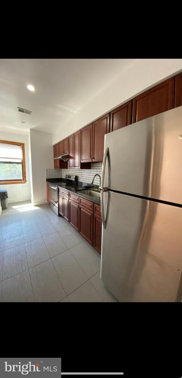 kitchen featuring appliances with stainless steel finishes, light tile patterned floors, tasteful backsplash, and sink