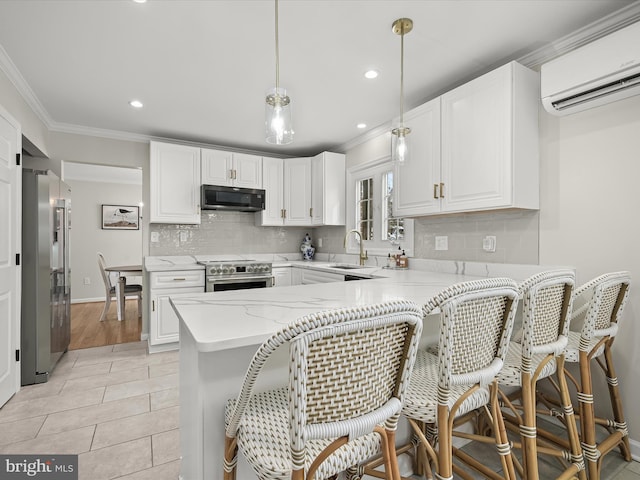 kitchen with an AC wall unit, white cabinets, appliances with stainless steel finishes, decorative light fixtures, and kitchen peninsula