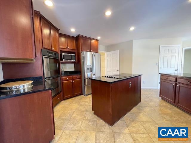 kitchen featuring appliances with stainless steel finishes, dark stone counters, and a kitchen island