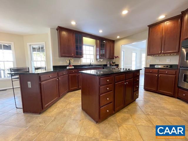 kitchen with light tile patterned floors, a kitchen island, stainless steel double oven, and sink