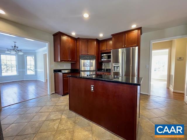 kitchen featuring an inviting chandelier, stainless steel appliances, light tile patterned flooring, ornamental molding, and a center island