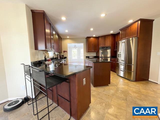 kitchen featuring a kitchen breakfast bar, a kitchen island, stainless steel appliances, and sink