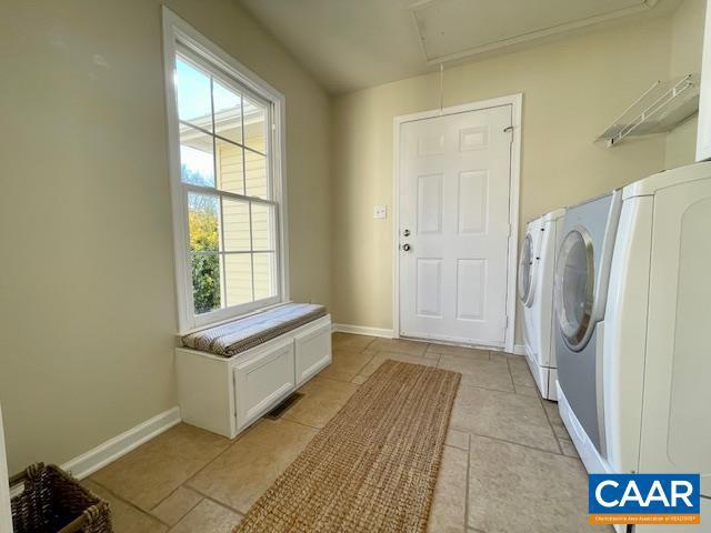 clothes washing area featuring washer and dryer, cabinets, and a wealth of natural light