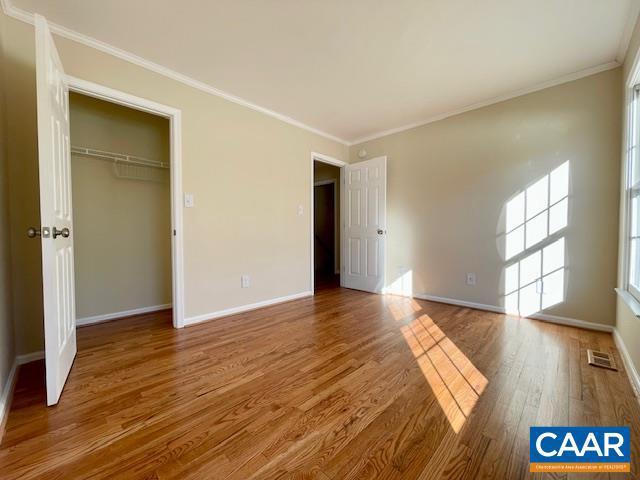 unfurnished bedroom with hardwood / wood-style flooring, a closet, and crown molding