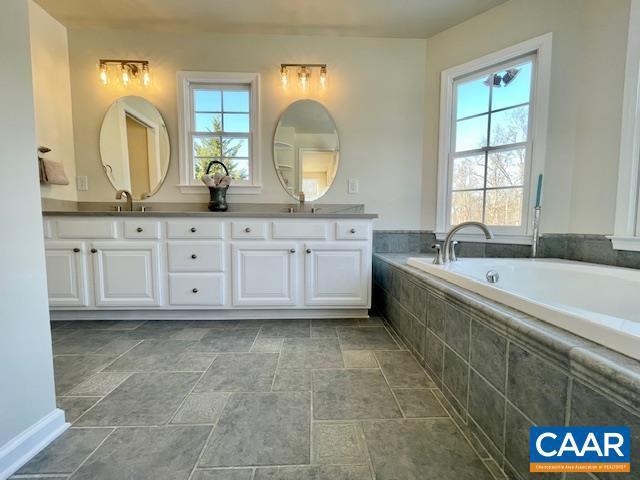 bathroom with a relaxing tiled tub and vanity