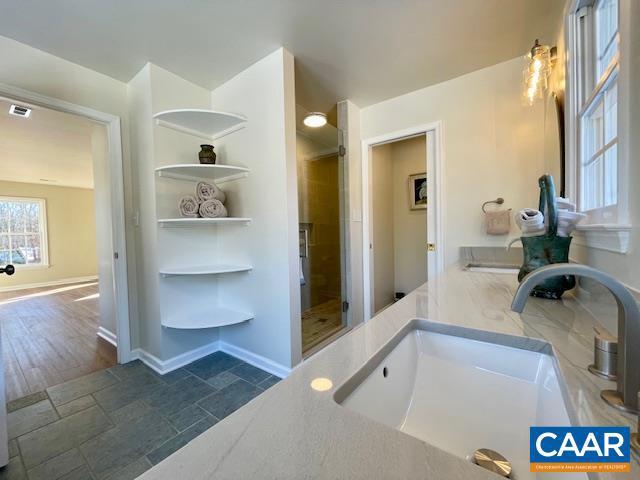 bathroom featuring a shower with shower door and sink