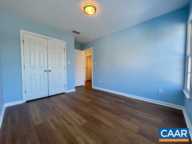 unfurnished bedroom with a closet and dark wood-type flooring