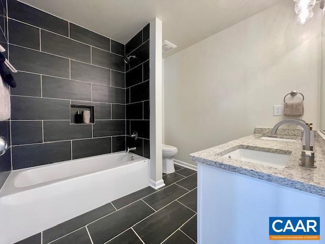 full bathroom featuring toilet, tiled shower / bath, tile patterned floors, and vanity