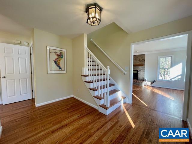 stairs featuring a brick fireplace, hardwood / wood-style flooring, and an inviting chandelier