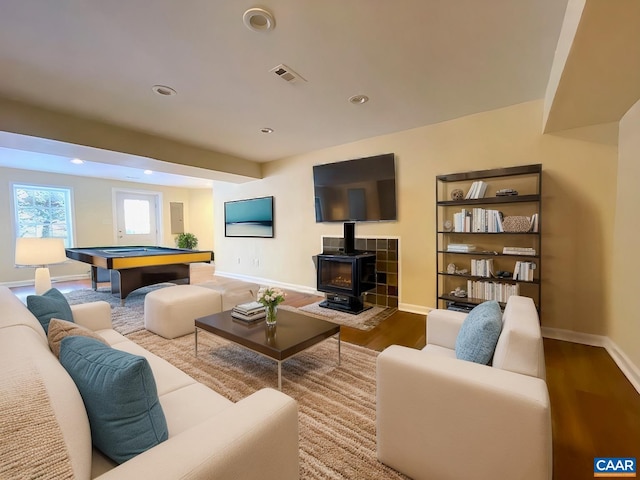 living room featuring pool table, a wood stove, and hardwood / wood-style floors