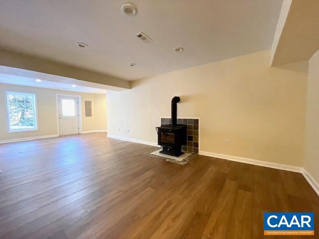 unfurnished living room with a wood stove and dark hardwood / wood-style flooring