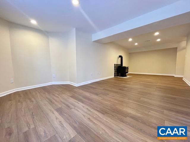 basement with a wood stove and hardwood / wood-style floors