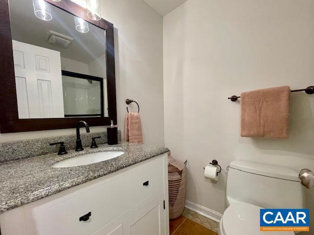 bathroom with toilet, vanity, and tile patterned flooring