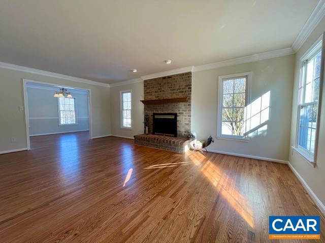 unfurnished living room with dark wood-type flooring, a brick fireplace, and ornamental molding