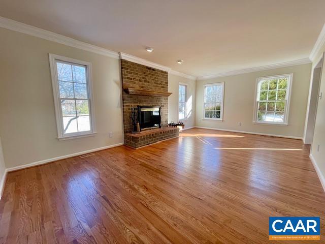 unfurnished living room with wood-type flooring, crown molding, and a fireplace