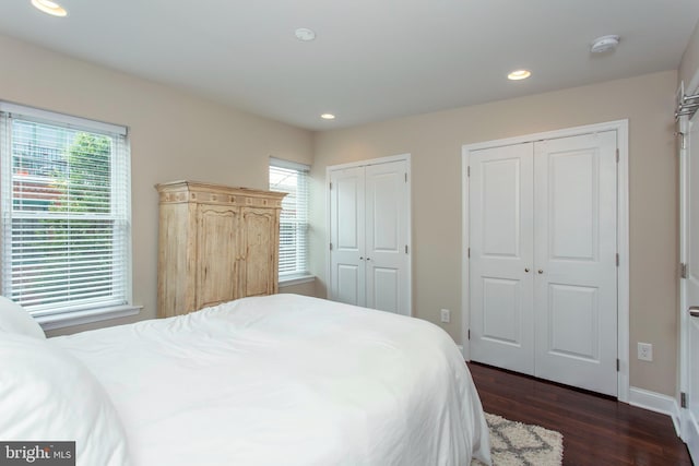 bedroom with dark hardwood / wood-style flooring and multiple closets