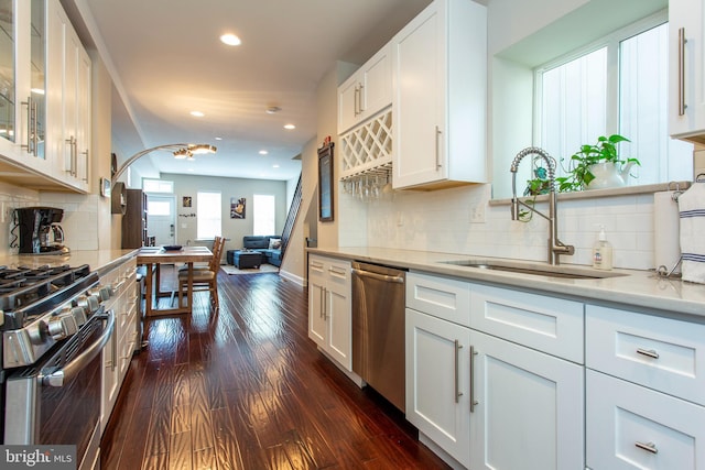 kitchen with stainless steel appliances, dark wood-type flooring, sink, white cabinetry, and backsplash