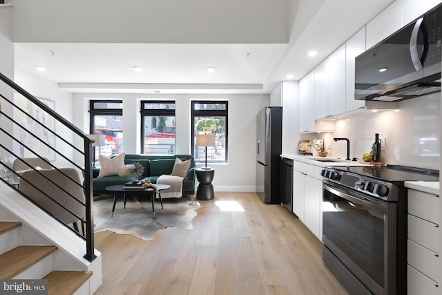 kitchen with appliances with stainless steel finishes, light hardwood / wood-style floors, white cabinets, and sink