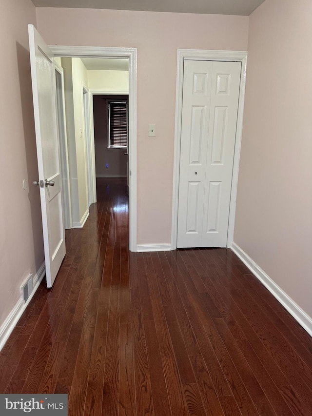 unfurnished bedroom featuring a closet and dark hardwood / wood-style floors