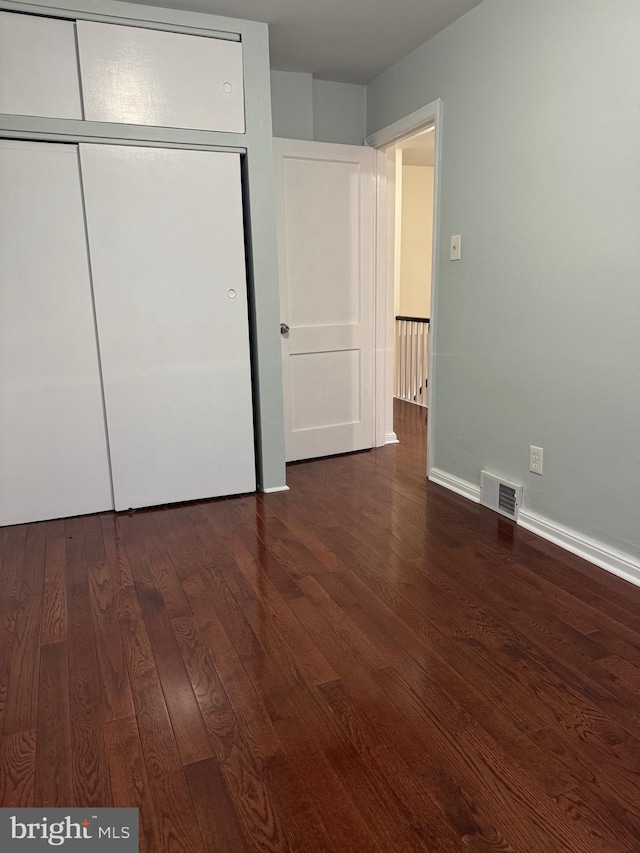 unfurnished bedroom with dark hardwood / wood-style flooring and a closet