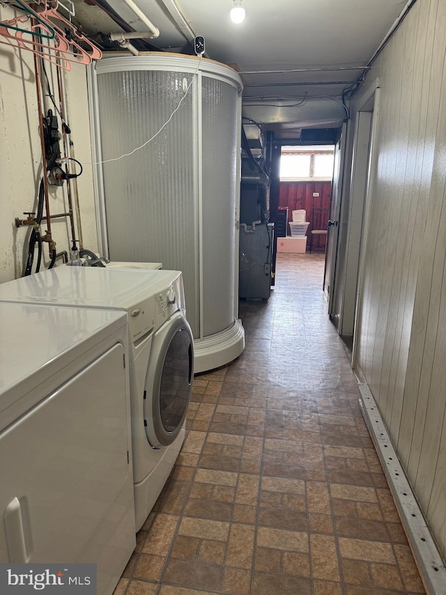 washroom featuring washer and clothes dryer and wood walls