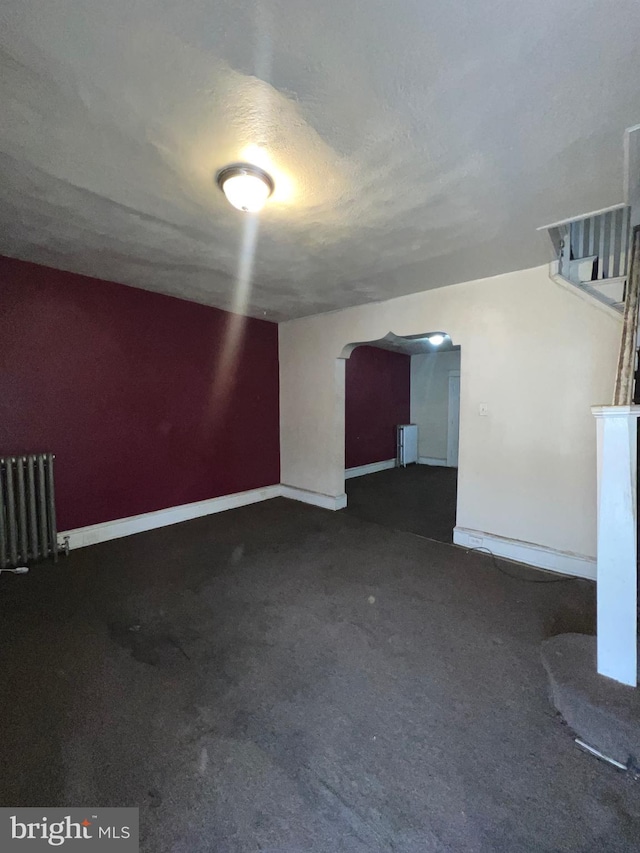 additional living space featuring radiator and a textured ceiling