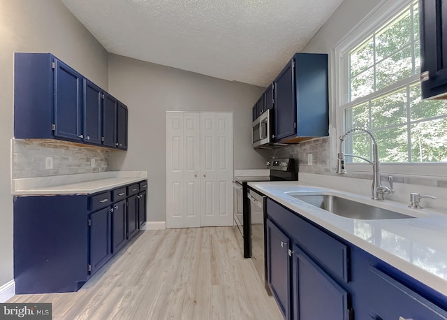 kitchen with sink, appliances with stainless steel finishes, tasteful backsplash, and blue cabinets