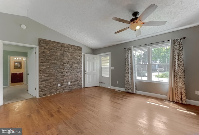 empty room featuring light hardwood / wood-style floors, a textured ceiling, lofted ceiling, and ceiling fan