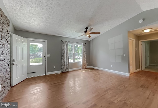 interior space with ceiling fan, vaulted ceiling, a textured ceiling, and hardwood / wood-style flooring