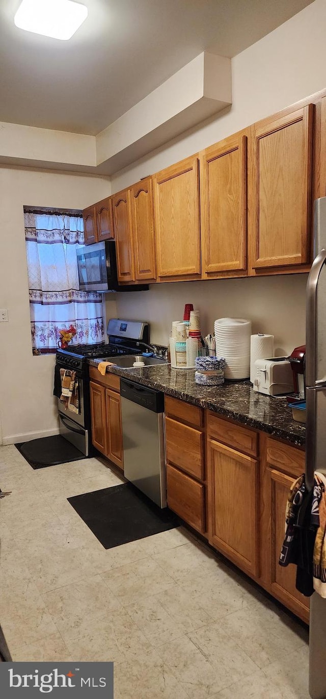 kitchen with appliances with stainless steel finishes and dark stone counters