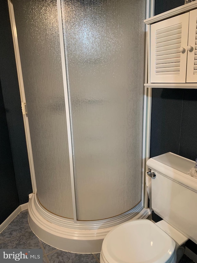 bathroom with a shower with shower door, tile patterned floors, and toilet