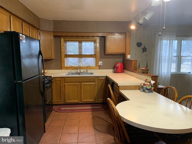 kitchen with black appliances, light tile patterned floors, kitchen peninsula, and sink