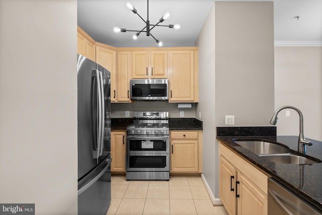 kitchen with light tile patterned floors, an inviting chandelier, appliances with stainless steel finishes, dark stone countertops, and sink