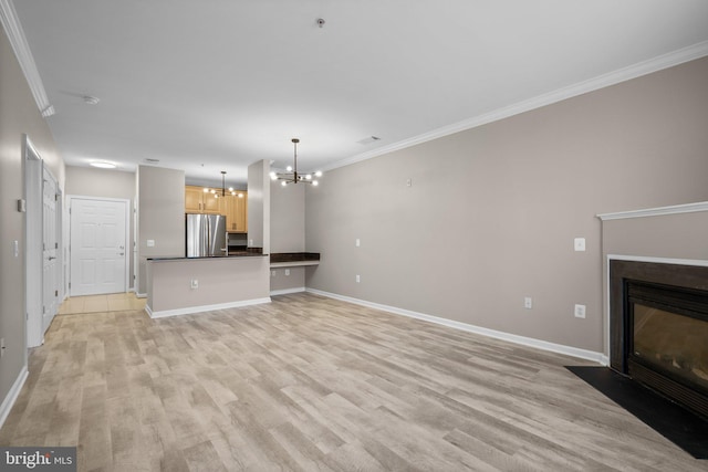 unfurnished living room featuring an inviting chandelier, ornamental molding, and light wood-type flooring