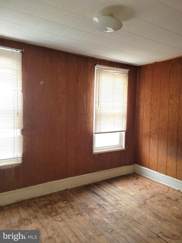 empty room featuring wooden walls and wood-type flooring