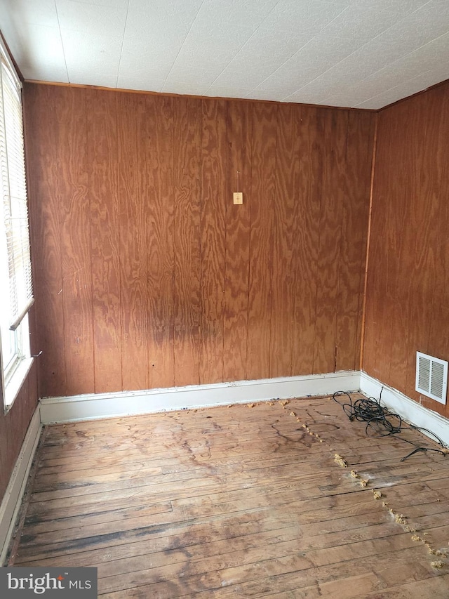 unfurnished room with hardwood / wood-style floors and wood walls