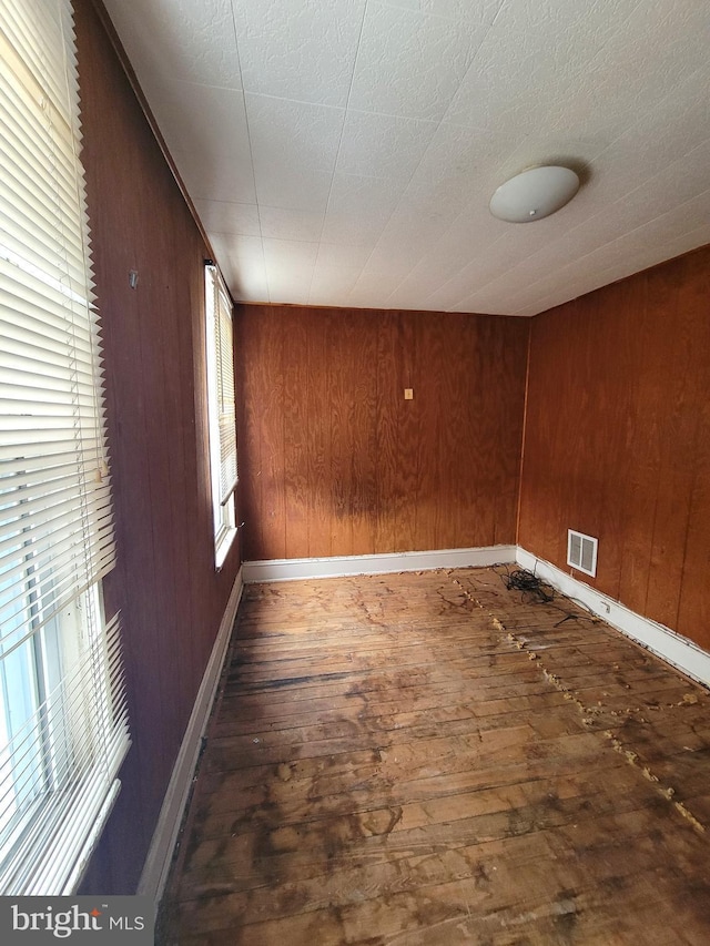 empty room with dark hardwood / wood-style flooring and wood walls