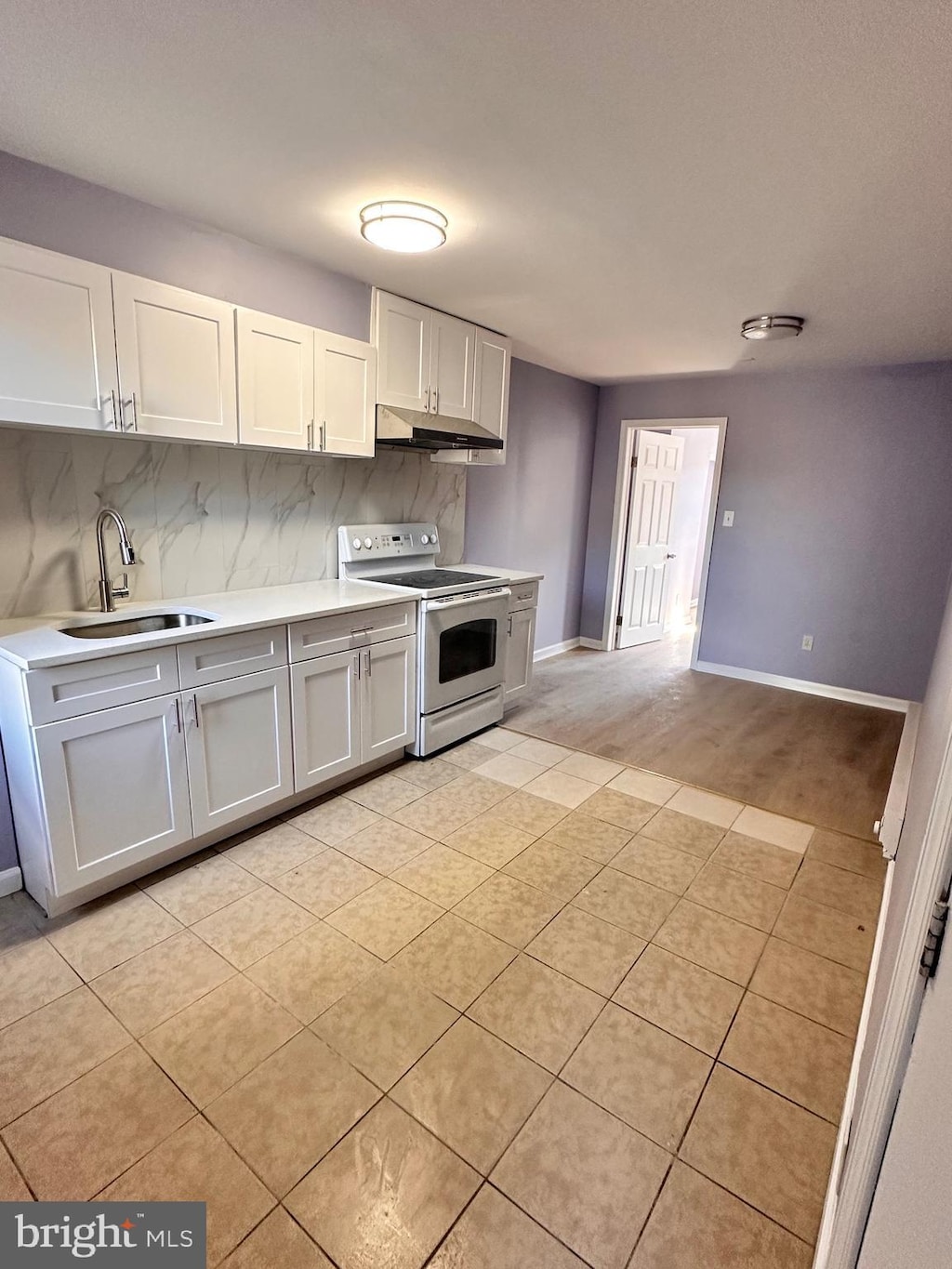 kitchen with white range with electric stovetop, decorative backsplash, sink, white cabinetry, and light tile patterned flooring