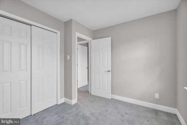 unfurnished bedroom featuring light colored carpet and a closet