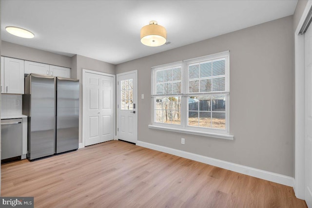 kitchen featuring appliances with stainless steel finishes, light hardwood / wood-style flooring, and white cabinetry