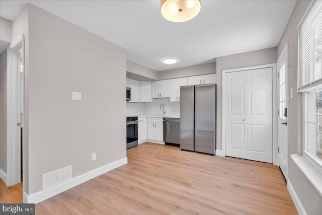 kitchen featuring stainless steel appliances, light hardwood / wood-style floors, white cabinets, and sink