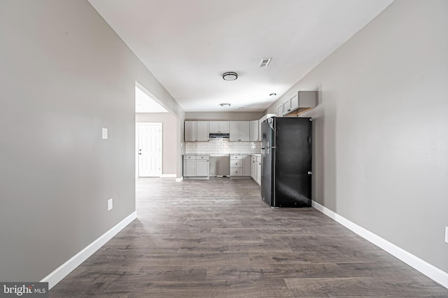 kitchen with dark hardwood / wood-style flooring, black refrigerator, gray cabinets, and backsplash