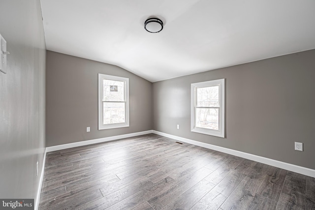 spare room featuring lofted ceiling and dark hardwood / wood-style flooring