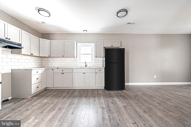 kitchen with black fridge, white cabinets, and light hardwood / wood-style floors