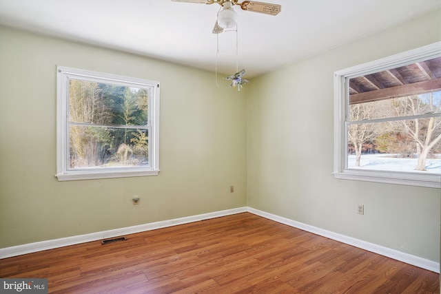 empty room featuring ceiling fan, plenty of natural light, and hardwood / wood-style floors